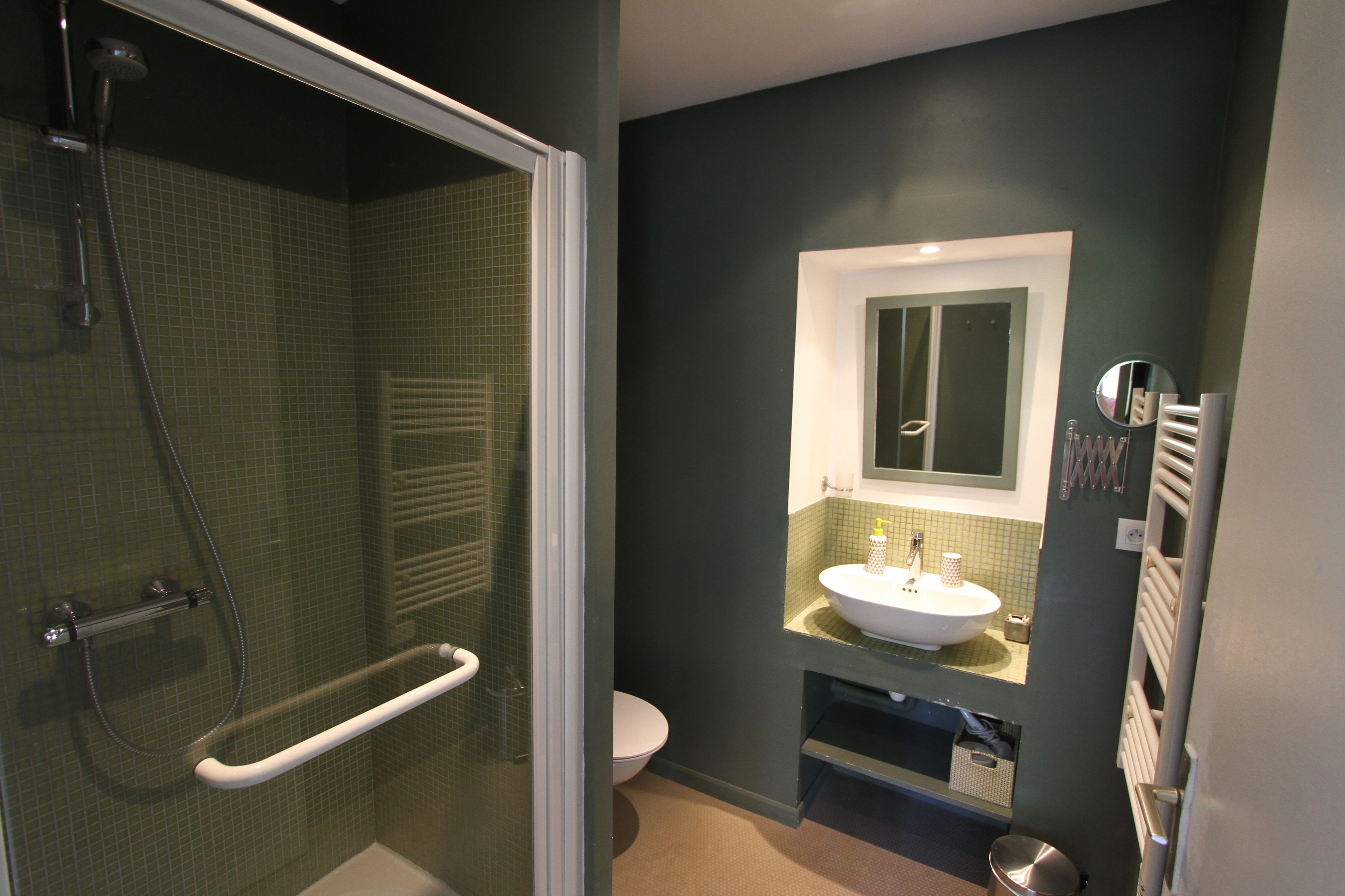 A bathroom with a glass-enclosed shower, a white sink, and a toilet.