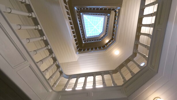 Un escalier en colimaçon surmonté d’une lucarne centrale.