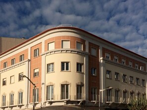 Un immeuble à plusieurs étages, doté d’une façade incurvée, de grandes fenêtres et d’un toit recouvert de tuiles rouges.
