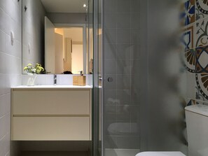 Une salle de bain moderne avec une douche à parois de verre, un lavabo blanc et un miroir au-dessus.