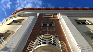 Un bâtiment doté d’une façade symétrique, de grandes fenêtres et d’un balcon central.