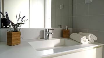A modern bathroom with a white sink, a mirror, and two wooden containers.