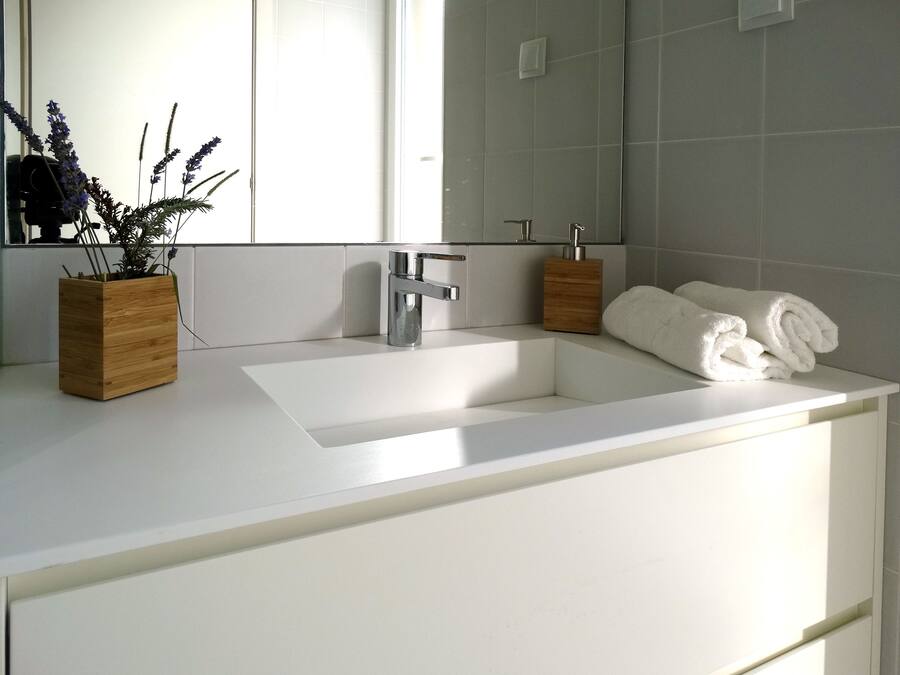 A modern bathroom with a white sink, a mirror, and two wooden containers.