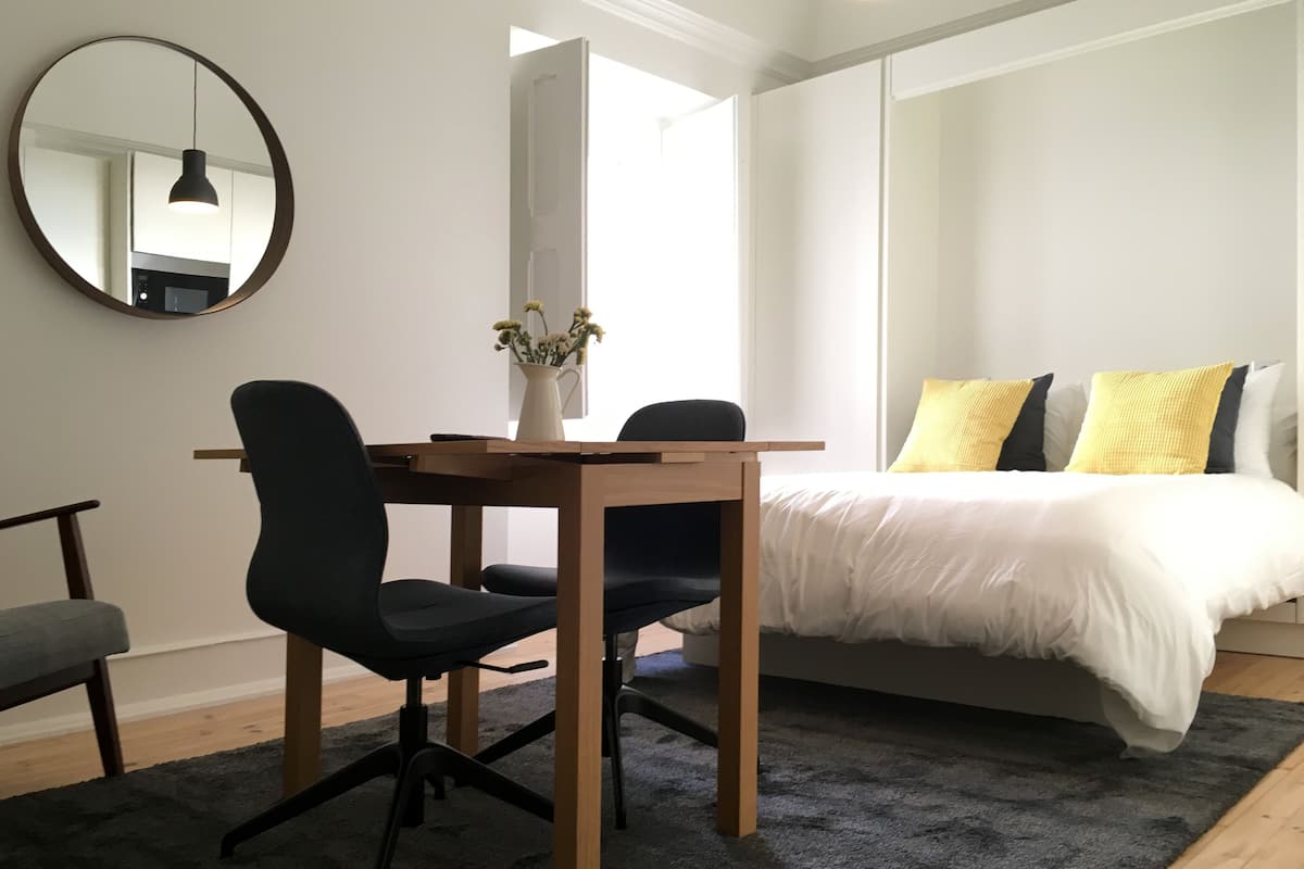 A modern bedroom with a bed, bedside table, and a desk with two chairs.