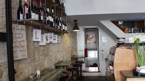 A restaurant interior with wooden tables and chairs, a wine rack, and a menu board. - Linha22 GuestHouse (Porto)