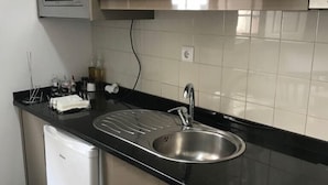 A modern kitchen with a built-in microwave, stainless steel sink, and a compact dishwasher. - Linha22 GuestHouse (Porto)