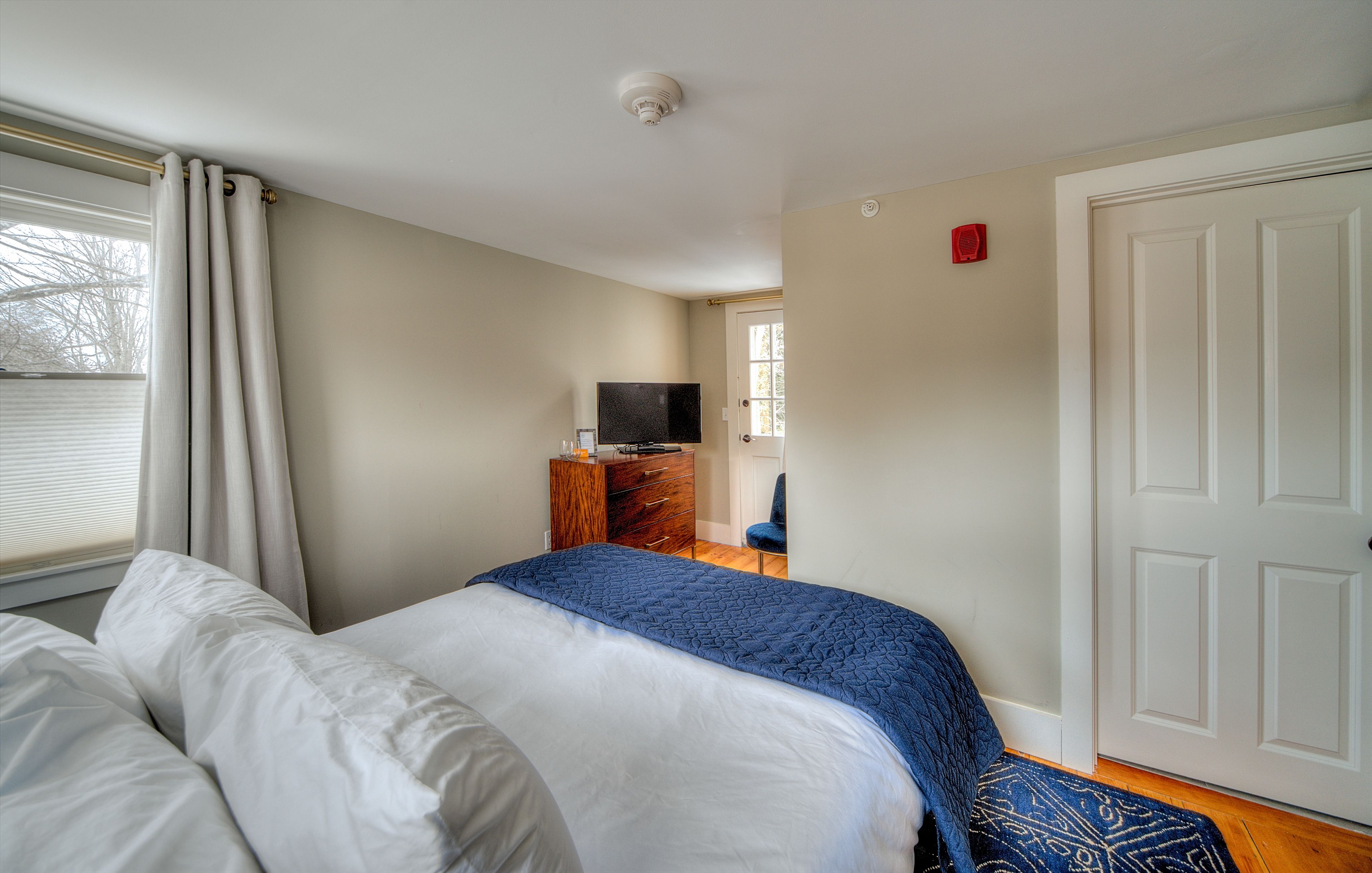 Quarto com cama, penteadeira, televisão e porta.