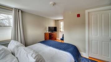 Quarto com cama, penteadeira, televisão e porta.