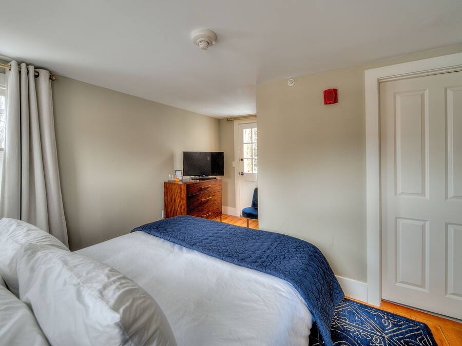 Quarto com cama, penteadeira, televisão e porta.