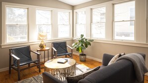 A cozy living room with a sofa, two chairs, a small table, a lamp, and a potted plant. - The Sailmaker's House (Portsmouth)
