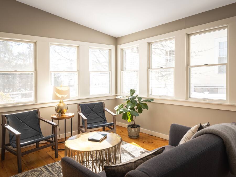 Un salon confortable avec un canapé, deux fauteuils, une petite table, une lampe et une plante en pot.