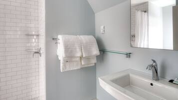 Uma casa de banho moderna com chuveiro, lavatório e espelho.