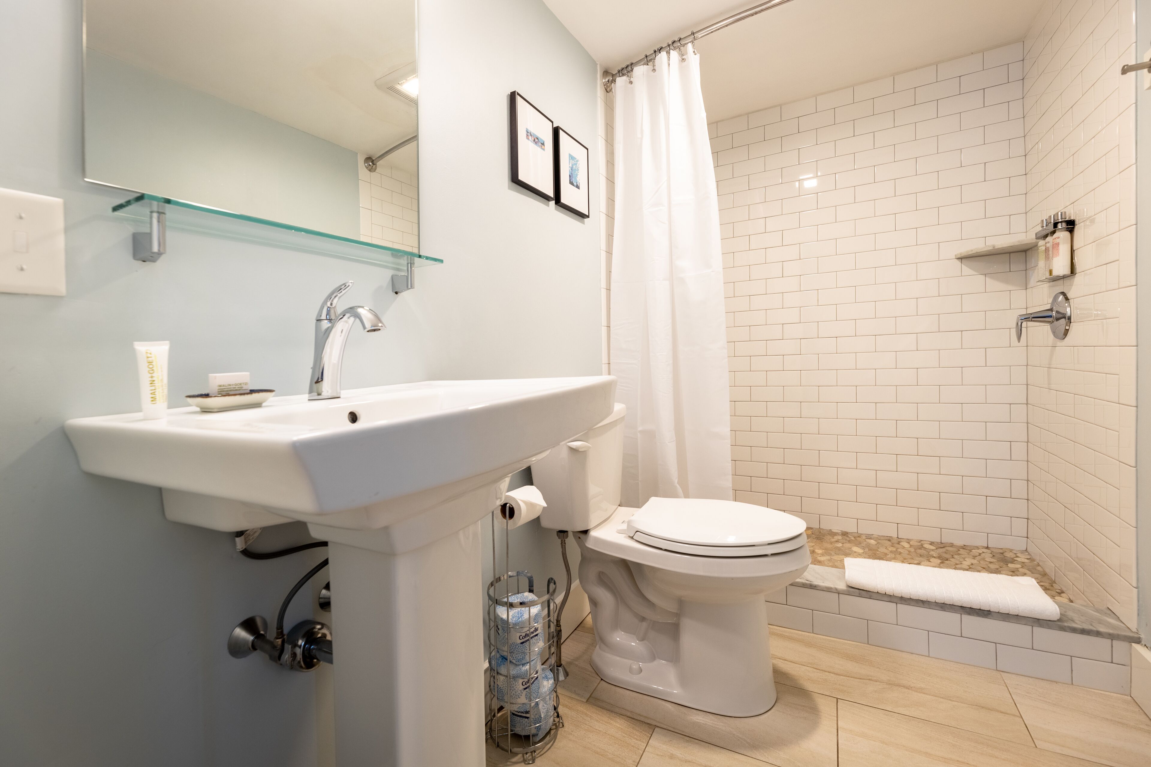 A bathroom with a white sink, toilet, and shower area.