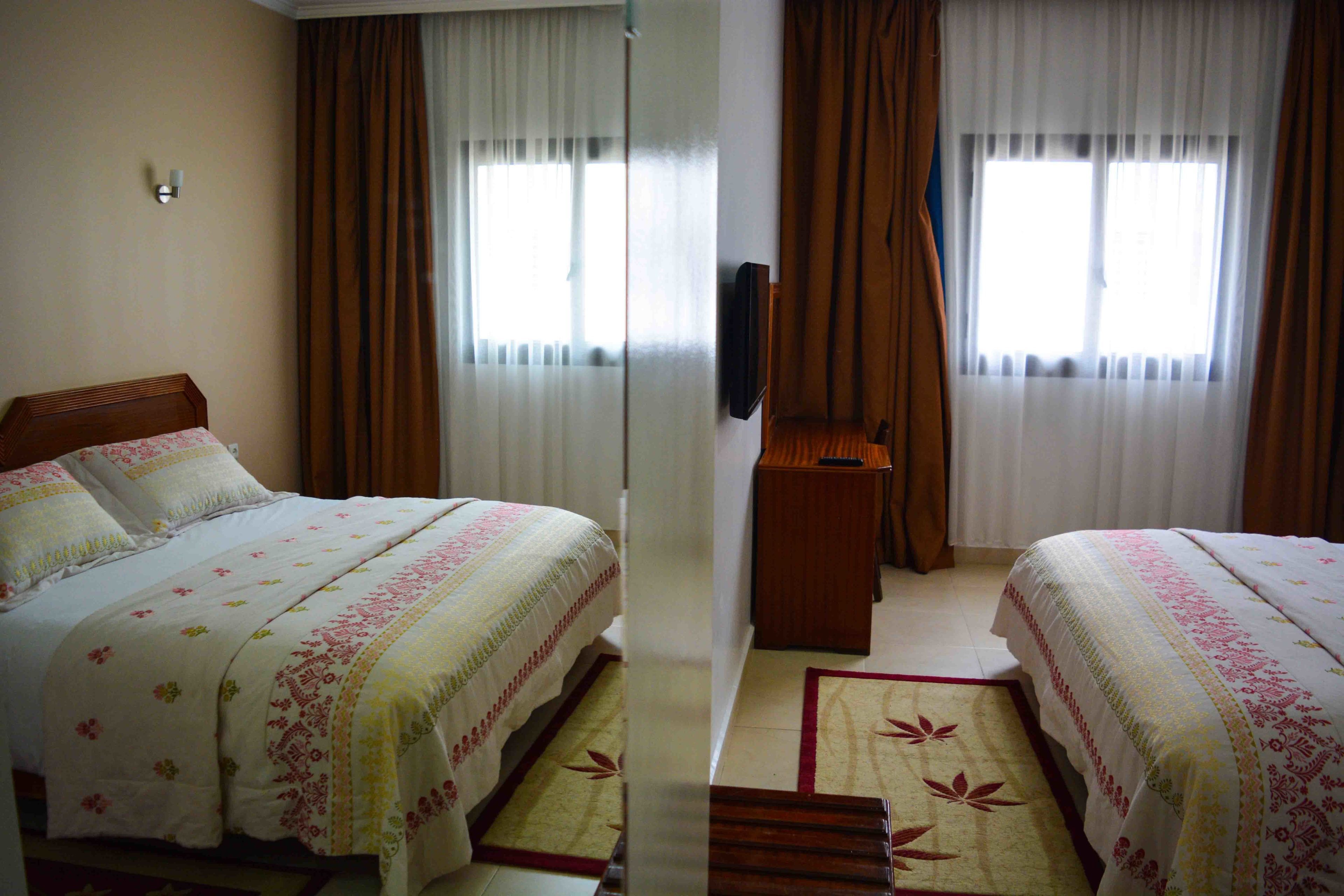 A hotel room with two beds, a TV, and a small wooden table.