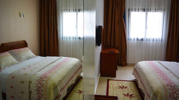 A hotel room with two beds, a TV, and a small wooden table.