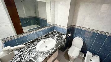 Un baño con lavamanos de mármol, inodoro, bidé y zona de ducha.