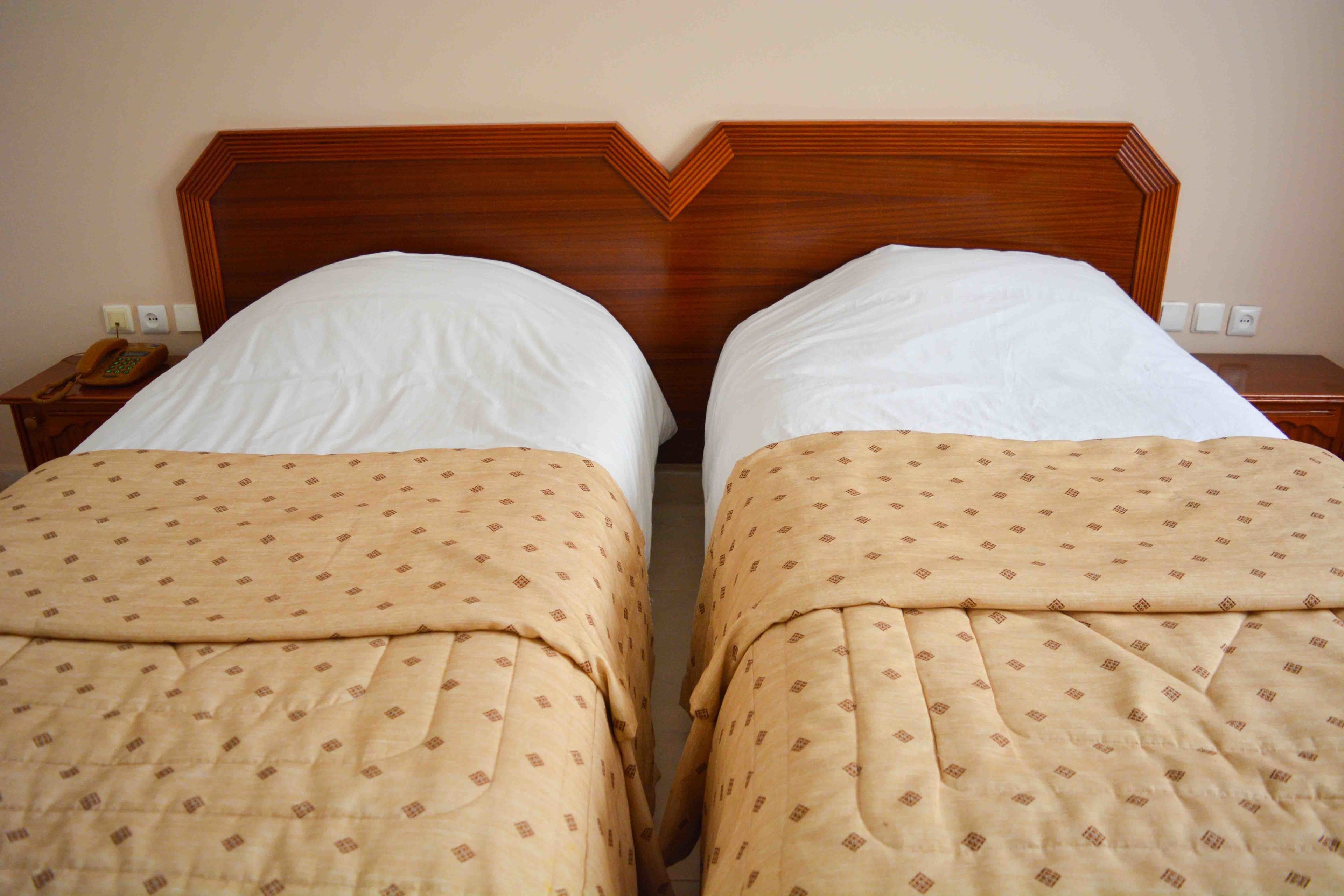 A double bed with a wooden headboard, two bedside tables, and a telephone on one of the tables.