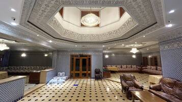 A luxurious interior with a patterned floor, ornate ceiling, and seating areas.