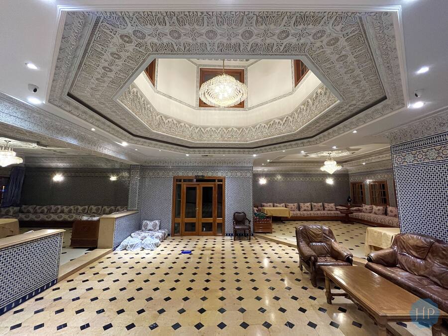 A luxurious interior with a patterned floor, ornate ceiling, and seating areas.