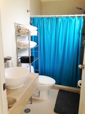 Un baño con lavamanos blanco, inodoro y cortina de ducha azul.