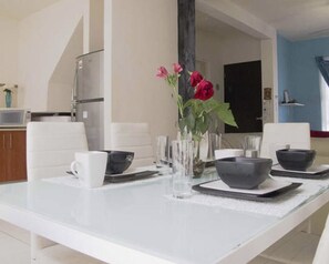 A dining area with a white table set for four, including bowls, cups, and a vase with flowers. - Casa en Cancún México 3987 by Sinbad (Cancun)