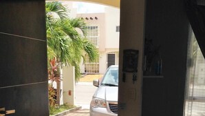 Una puerta que da a un área de estacionamiento con un coche aparcado.