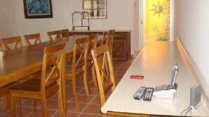 A dining area with a long table and chairs, a ceiling fan, and a door leading to a bright room. - Casa Vacacional Cancún 3270 by Sinbad (Cancun)