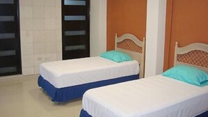 A room with two beds, each with a wooden headboard and a blue skirt. There is a white air conditioning unit on the wall. - Casa Vacacional Cancún 3270 by Sinbad (Cancun)