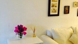 A small white table with a vase of flowers and a candle, positioned next to a white sofa with cushions. - Hacienda San José 647 by Sinbad (Playa del Carmen)