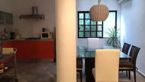 A dining area with a glass table and chairs, a hanging light fixture, and a view through a window. - Hacienda San José 647 by Sinbad (Playa del Carmen)