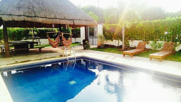 A swimming pool with a thatched-roof structure, lounge chairs, and a small garden area. - Apartamento Real Ibiza 639 by Sinbad (Playa del Carmen)