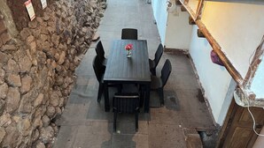 A stone wall, a table with chairs, and a small light fixture. - Casa Intihuatana - Hostel (Pisac)