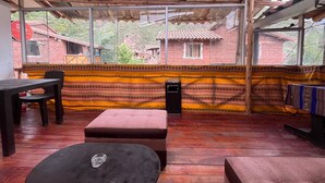 A room with a wooden ceiling, large windows, a patterned wall, and a wooden floor. - Casa Intihuatana - Hostel (Pisac)