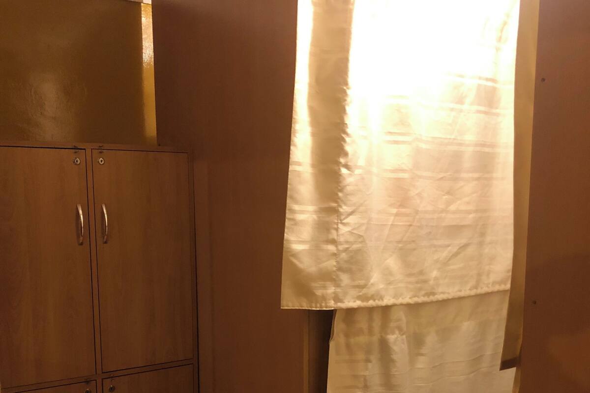 A room with wooden cabinets, a patterned floor, and a white curtain.