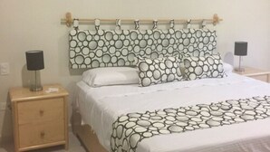 A bedroom with a bed, two bedside tables, a nightstand, and a wall with three circular decorations. - Residencial Allegranza 628 by Sinbad (Playa del Carmen)