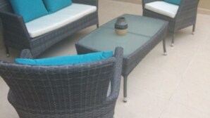 A patio with wicker furniture, including a sofa and chairs, and a small table with a decorative item. - Residencial Allegranza 628 by Sinbad (Playa del Carmen)
