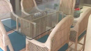 A dining area with a glass-top table and wicker chairs, a kitchen with a refrigerator, and a staircase leading to another level. - Residencial Allegranza 628 by Sinbad (Playa del Carmen)