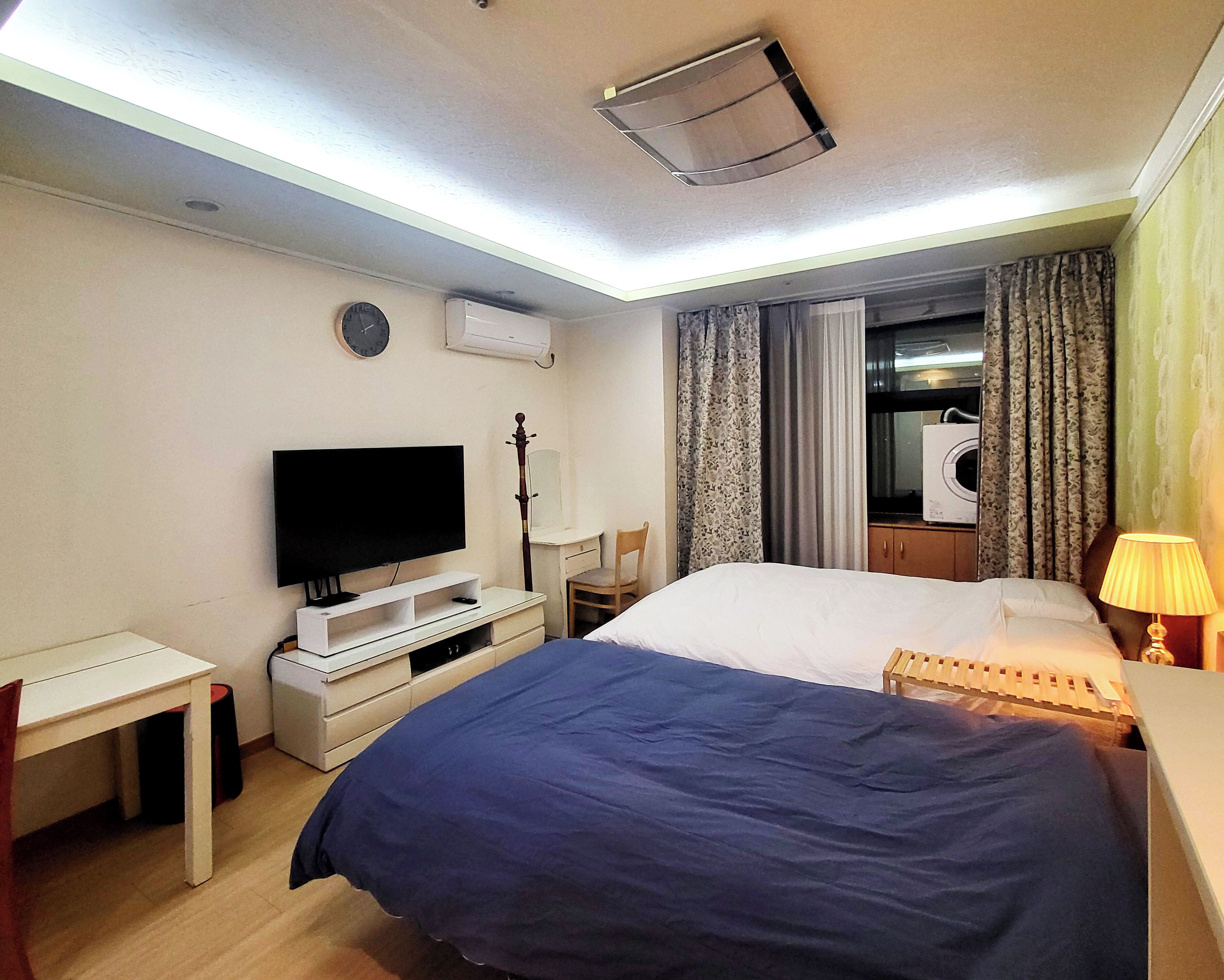 Une chambre d’hôtel équipée d’un lit, d’une télévision, d’un bureau, d’une chaise, d’un climatiseur et d’une lampe.