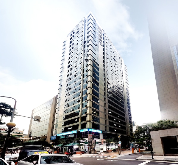 A tall, modern building with a glass facade and multiple floors. - Khan Residence (Seoul)