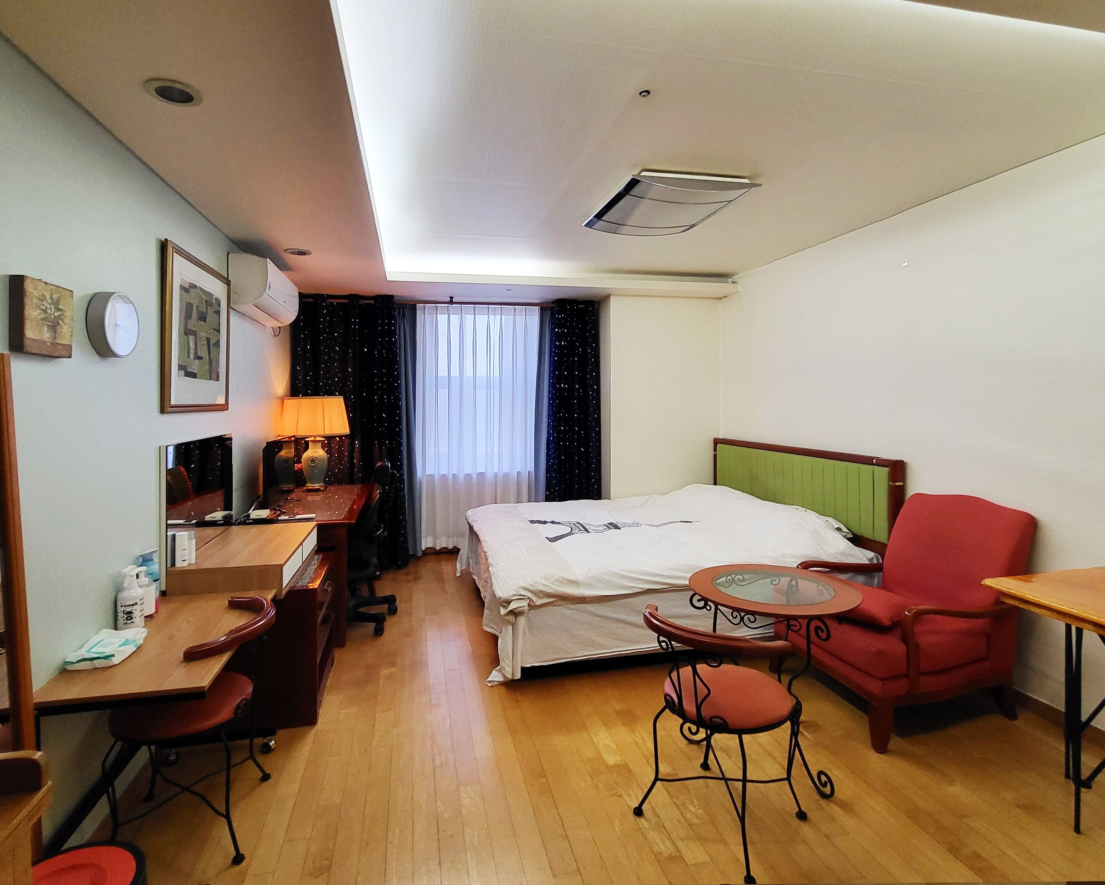 A hotel room with a bed, desk, chair, and a small table.