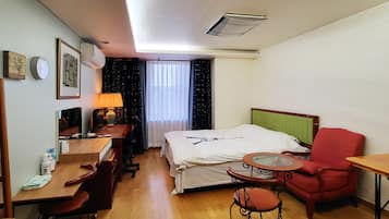 A hotel room with a bed, desk, chair, and a small table.