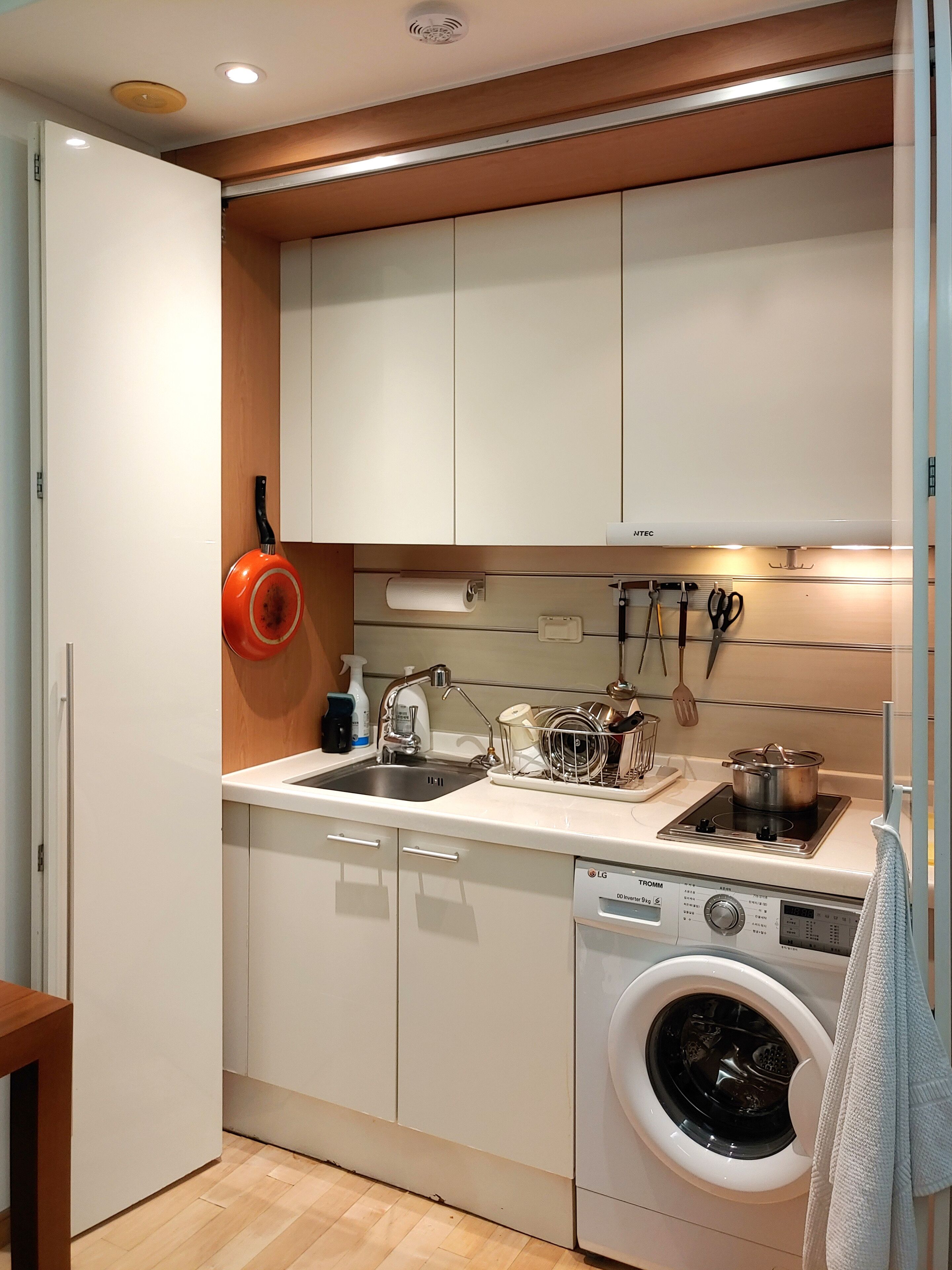 A compact kitchen with white cabinets, a built-in washing machine, and a sink.