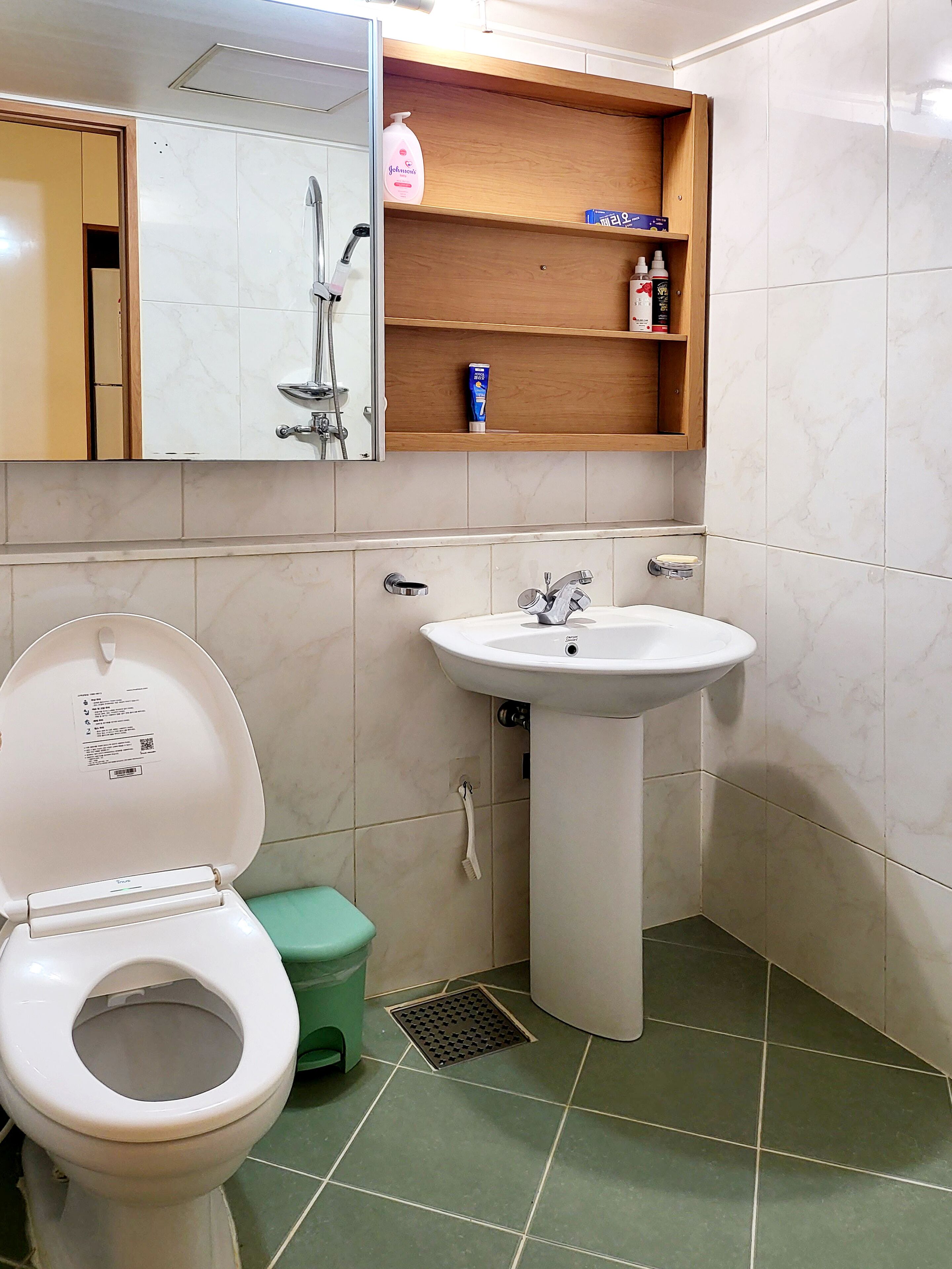 A bathroom with a toilet, sink, and a mirror above the sink.