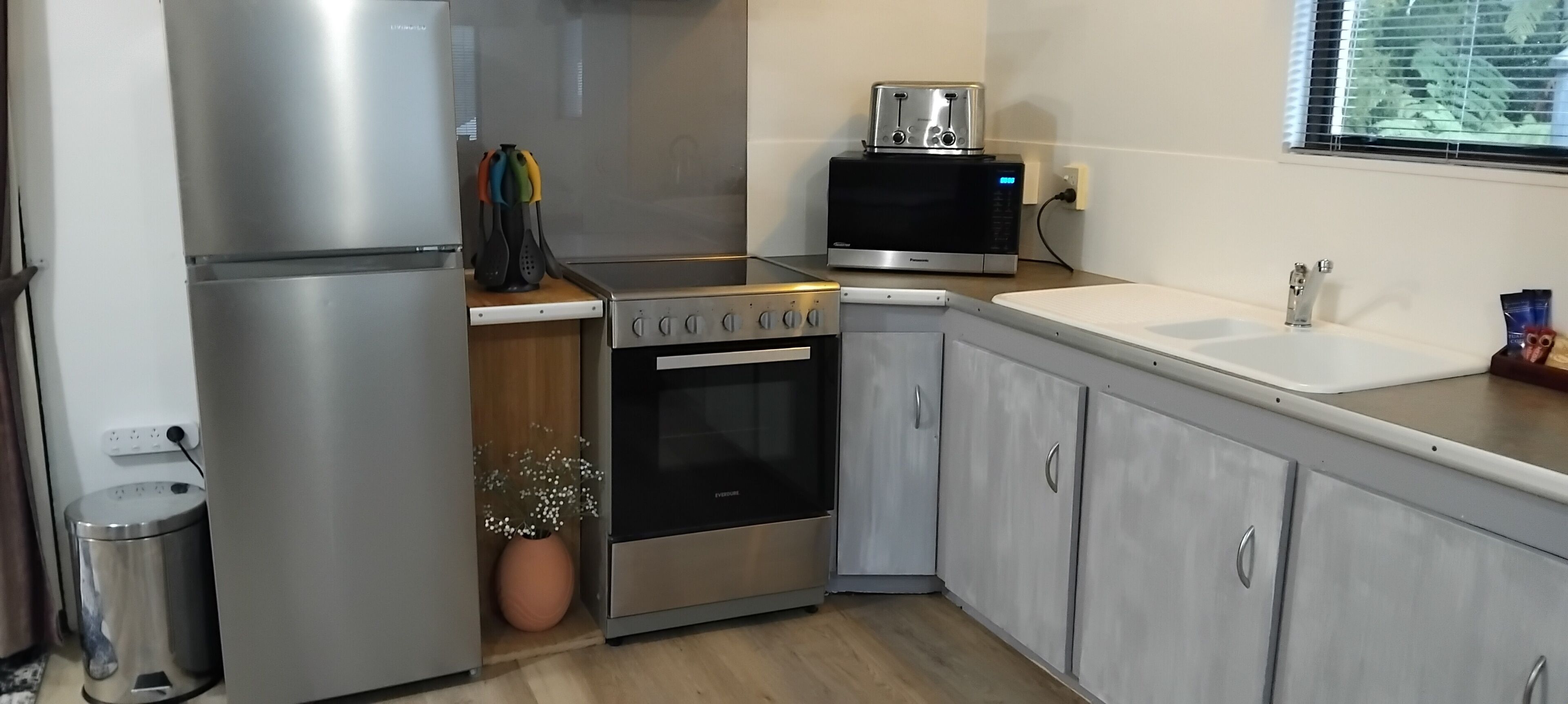 A kitchen with stainless steel appliances, a microwave, a sink, and a trash bin.