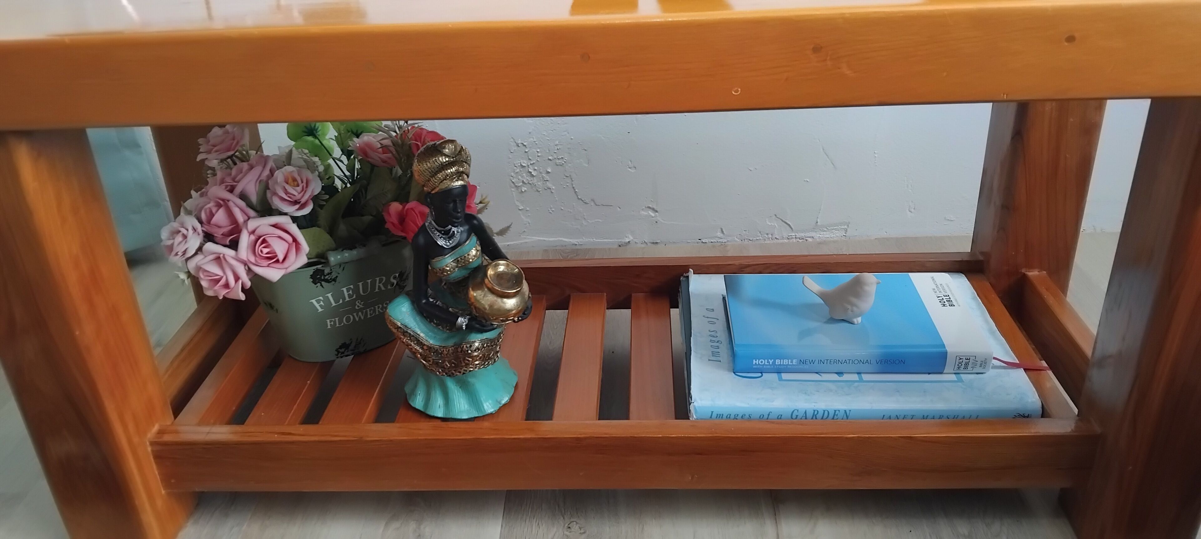 A wooden bench with a vase of flowers and a figurine on it, and a book titled 'Images of a Garden' on the bench.