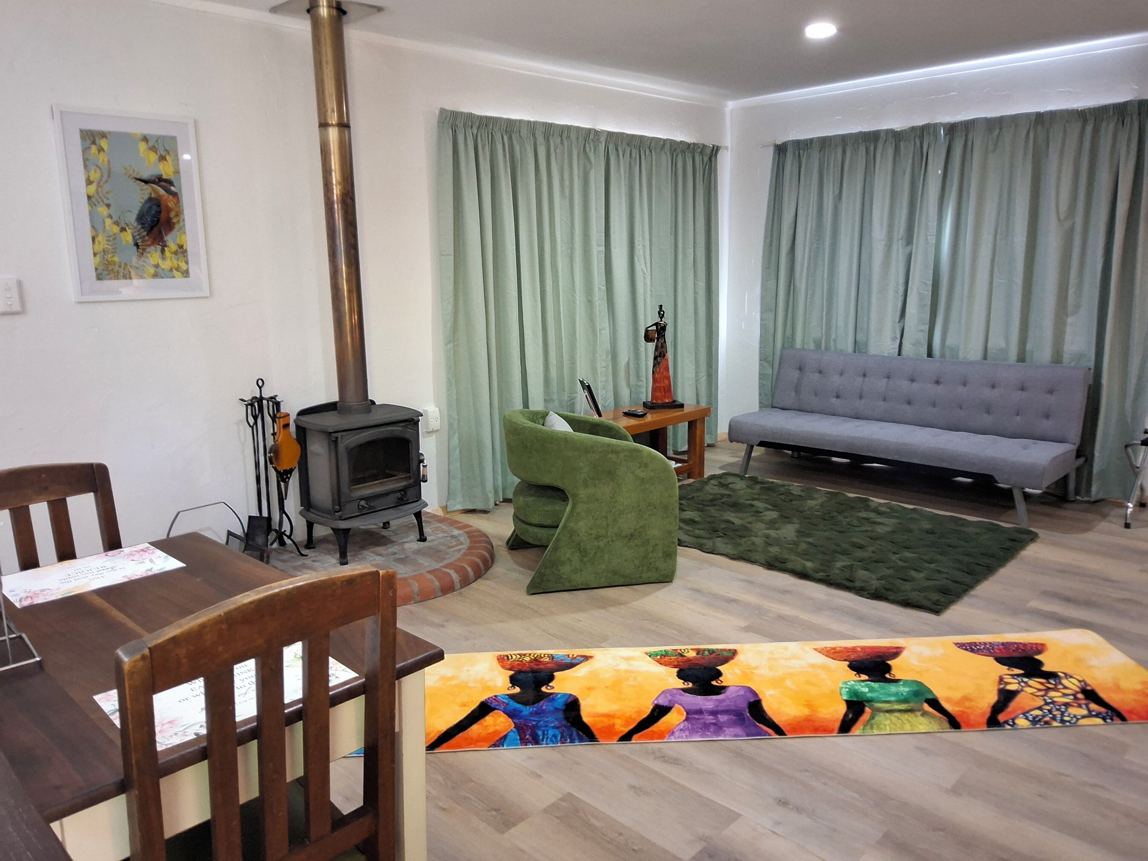 A living room with a sofa, a table, a chair, a fireplace, and a painting on the wall.
