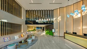 A modern lobby with a curved seating area, a reception desk, and a staircase leading to an upper level. - Satya Da Nang Hotel Han Market (Da Nang)