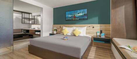Habitación de hotel moderna con una cama grande, una mesita de noche con una lámpara, una mesita auxiliar pequeña con un teléfono y un cuadro en la pared.
