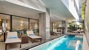 An indoor swimming pool with lounge chairs and a restaurant area. - Satya Da Nang Hotel Han Market (Da Nang)