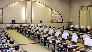Une salle de conférence avec des rangées de tables et de chaises, équipée de plaques nominatives et de sets de table.